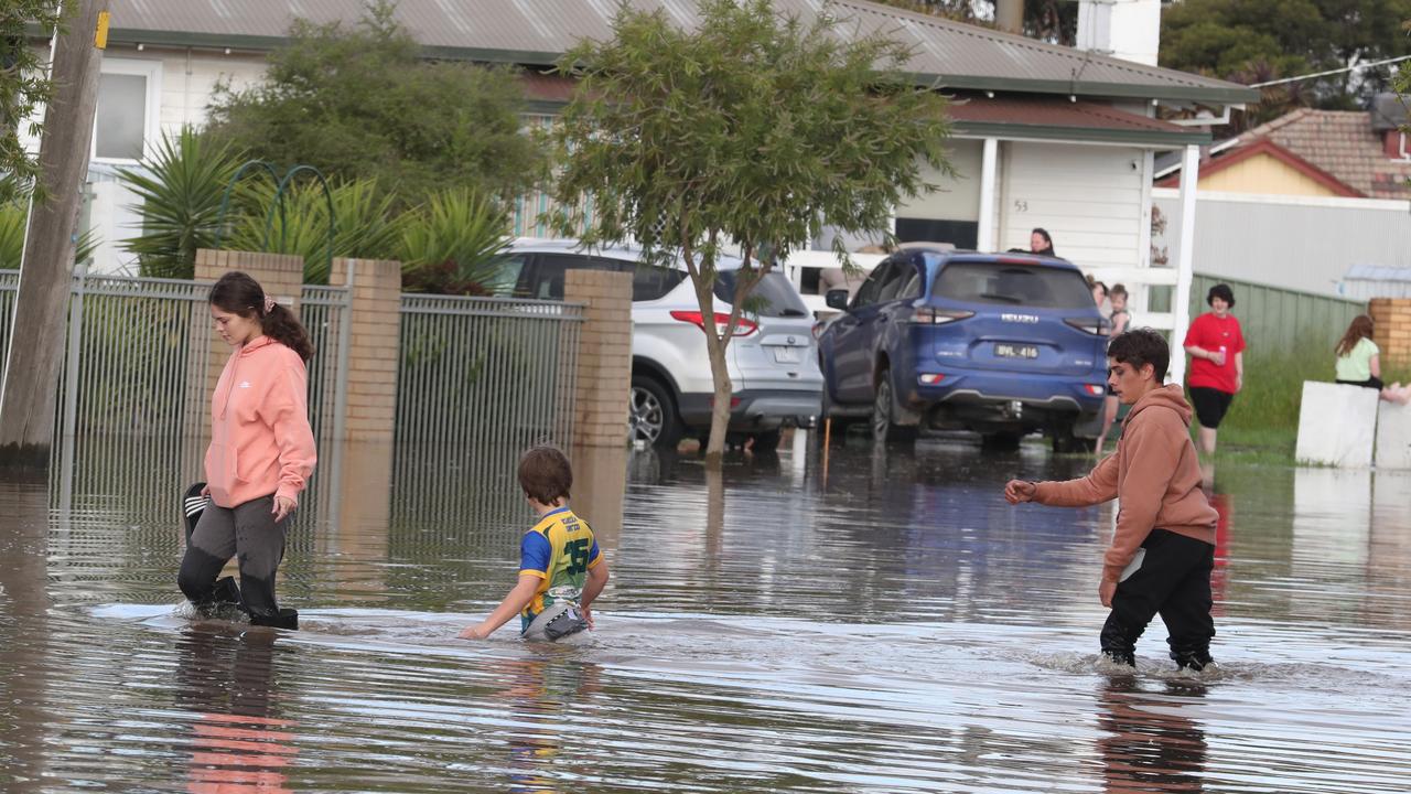 A family wades through the floodwaters in Shepparton. Picture: David Crosling