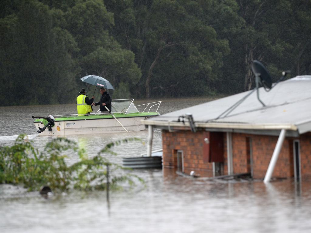 Residents row past a home that has been completely covered by floodwaters in the suburb of Vineyard, near Windsor. Picture: NCA NewsWire / Jeremy Piper