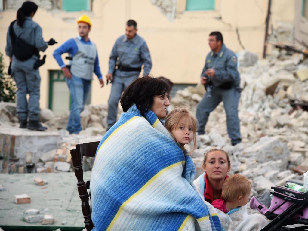 Victims sit among the rubble of a house after a strong earthquake hit Amatrice on August 24, 2016. Picture: AFP