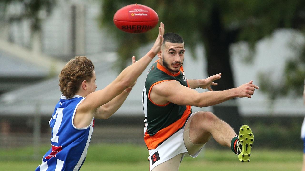 Essendon District: James Mifsud of Keilor Park kicks under pressure from Oak Park’s Zac Taylor. Picture: Hamish Blair