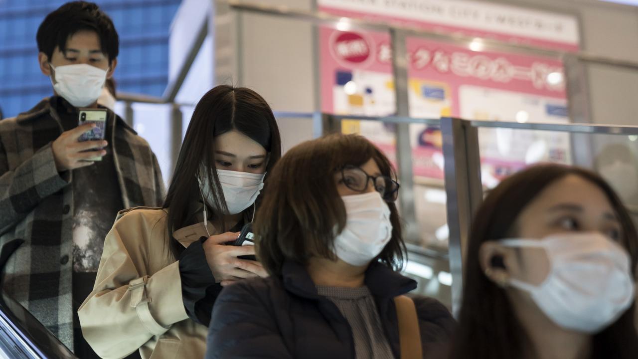 People wearing face masks ride on an escalator on March 14, 2020 in Osaka, Japan. Face masks are becoming the new normal. Picture: Tomohiro Ohsumi/Getty Images