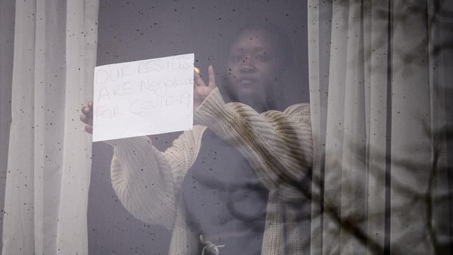 A woman holds up a sign reading ‘Our results are negative for COVID-19’ from her room at the Radisson Blu, in London on Wednesday. Picture: Getty Images