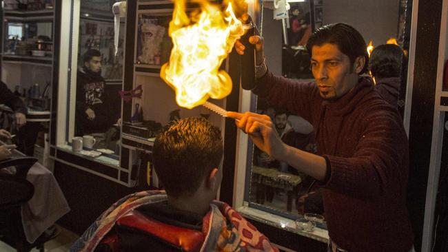 Ramadan Edwan, a Palestinian barber, uses fire in a hair-straightening technique with a client at his salon in the Rafah refugee camp, in the southern Gaza Strip. Picture: Mahmud Hams/AFP