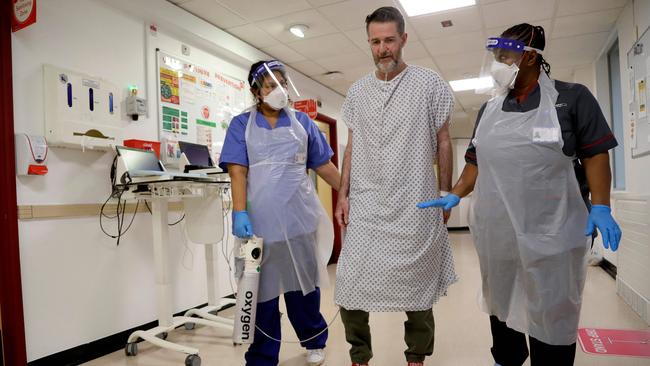 Felicia Kwaku, Associate Director of Nursing (R) and Anna Castellano, Matron (L), help Justin Fleming walk again after recovering from COVID-19 on the Cotton ward at King's College Hospital in London.