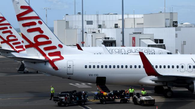 SYDNEY, AUSTRALIA - NCA NewsWire Photos FEBRUARY, 4, 2021: Virgin Australia baggage handlers are seen on the tarmac at Sydney Domestic Airport, Sydney. Virgin Australia says the end of JobKeeper in March could signal a mass shedding of workers if no further support is provided to the struggling aviation industry which has been out of action for almost one year. Picture: NCA NewsWire/Bianca De Marchi