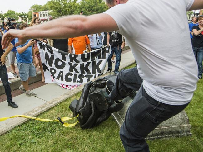 FILE - In this Aug. 14, 2017 file photo, a protester kicks the toppled statue of a Confederate soldier after it was pulled down in Durham, N.C.  Bombarded by the sharpest attacks yet from fellow Republicans, President Donald Trump on Thursday, Aug. 17, 2017, dug into his defense of racist groups by attacking members of own party and renouncing the rising movement to pull down monuments to Confederate icons.  (Casey Toth/The Herald-Sun via AP, File)/The Herald-Sun via AP)