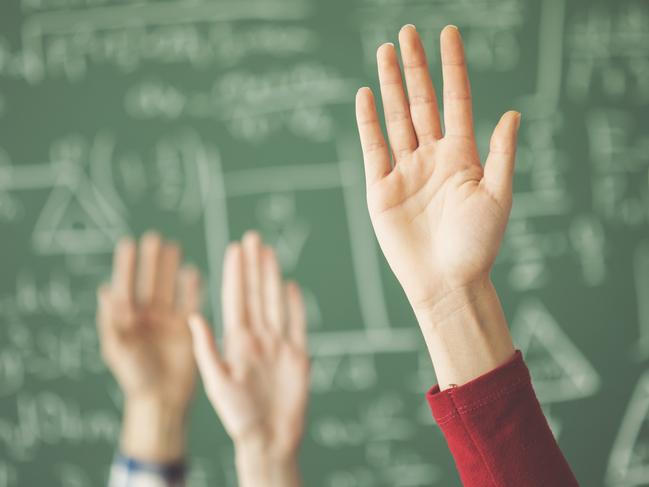 Students raised up hands green chalk board in classroom