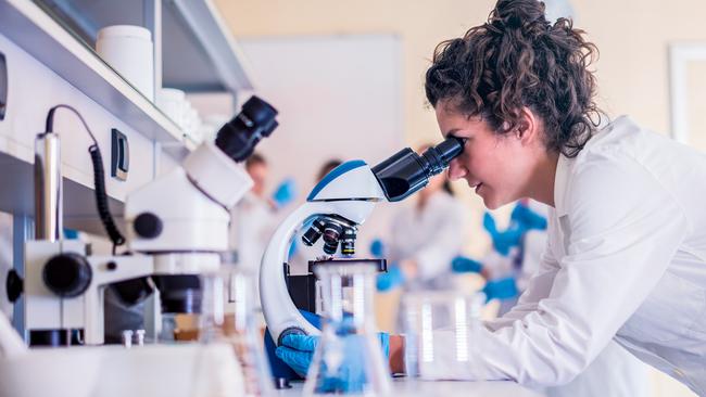 Scientist in lab doing research and using lab machines, test tubes, microscope and every laboratory equipment