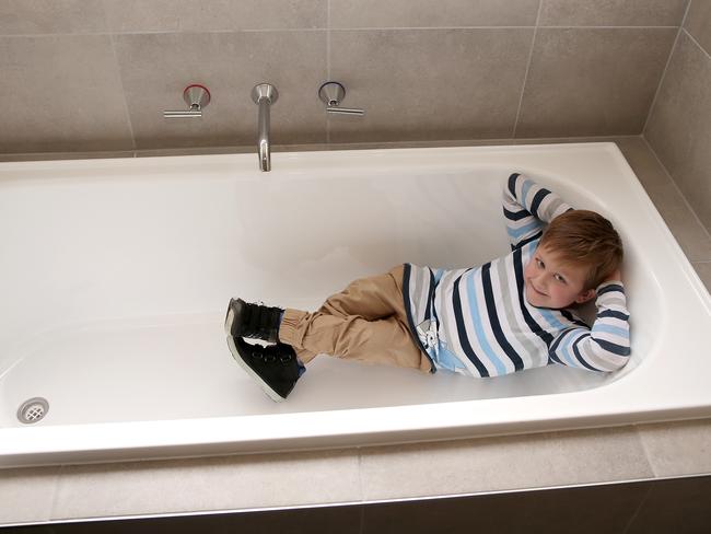 Single dad Aaron McArthur and his son, Abel, have moved into a specially built home to suit his disability. Abel in the new lowline bath. Picture: Alison Wynd