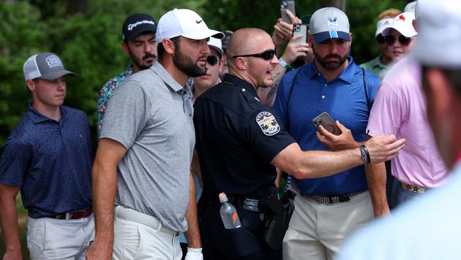 Spectators and a security guard look on as Scottie Scheffler prepares to take a drop on the fourth hole during the third round of the 2024 PGA Championship at Valhalla Golf Club.