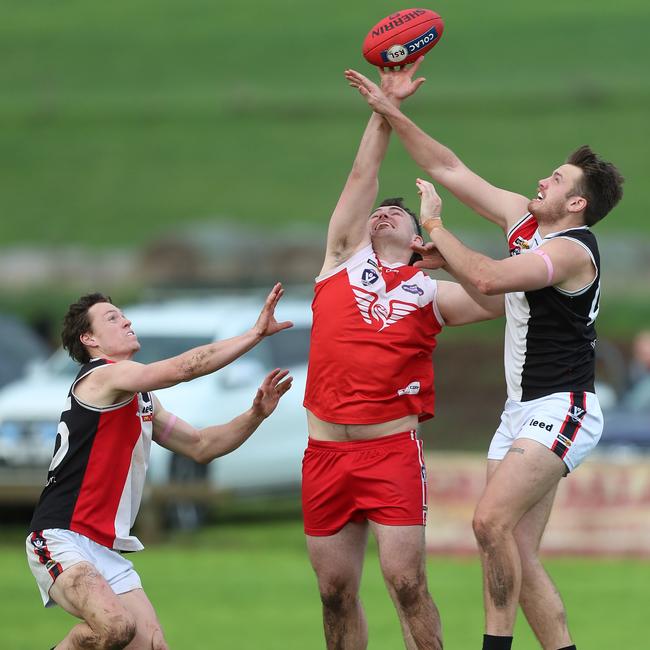 Alvie’s Dominic Dare battles two Birregurra opponents, Mitch Russell, left, and Kyle Davis. Dare needs one goal against Colac Imperials on Saturday to bring up his century. Picture: Yuri Kouzmin