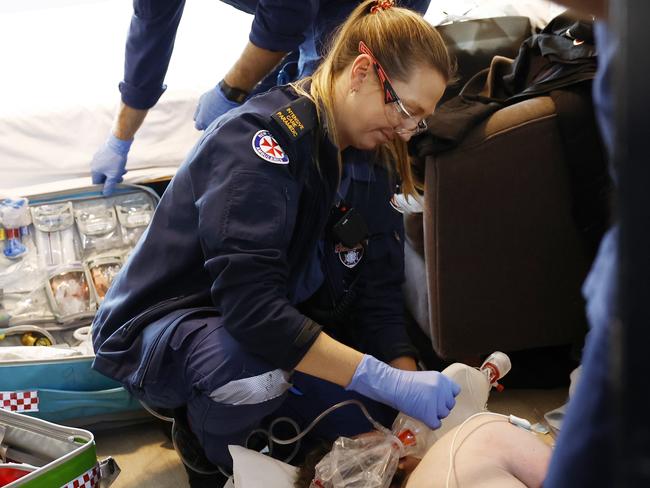 The team of paramedics treat the critically ill man at a hotel before he is transported to St Vincent’s Hospital emergency unit. Picture: Richard Dobson