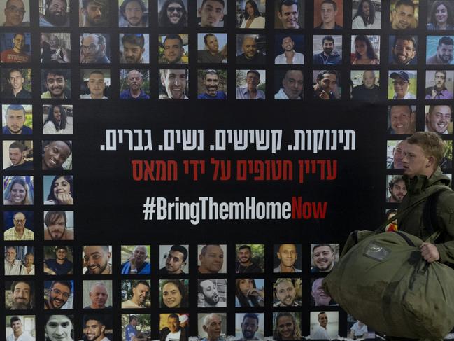 A soldier passes by a wall covered with photos of hostages held by Hamas. Picture: Getty Images