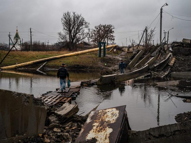 A local resident crosses a makeshift pontoon of wooden pallets alongside a destroyed bridge in Bakhmut, Donetsk region amid the Russian invasion of Ukraine. Picture: AFP