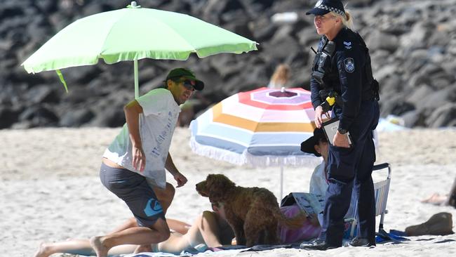 A police officer is seen on the beach at Burleigh Heads on the Gold Coast chatting to beachgoers. (AAP Image/Darren England)