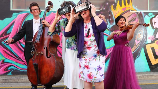 MUSIC TO EARS: ASO double bass player Harley Gray with project volunteer Jan O'Donnell, project co-ordinator Alison Campbell and violinist Shirin Lim, wearing a Jaimie Sortino gown. Shirin’s make-up was by Mandy Nash for Hair and Make-Up. Picture: TAIT SCHMAAL