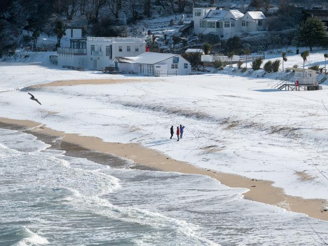 People walk on the snow covering the sand at Carbis Bay as snow arrives in St Ives on February 28, 2018 in Cornwall, England. Freezing weather conditions dubbed the “Beast from the East” has brought snow and sub-zero temperatures to many parts of the UK. Amber warnings are in place in northern England, the East Midlands, London, the d south-east of England. Scotland’s weather warning has been upgraded to red. Picture: Getty Images