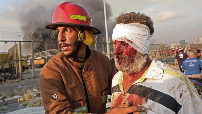 A fireman helps a wounded man away from the blast site. Picture: AFP