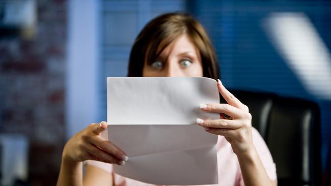 A woman looking at her mail (letter or bills)  in disbelief, shock!