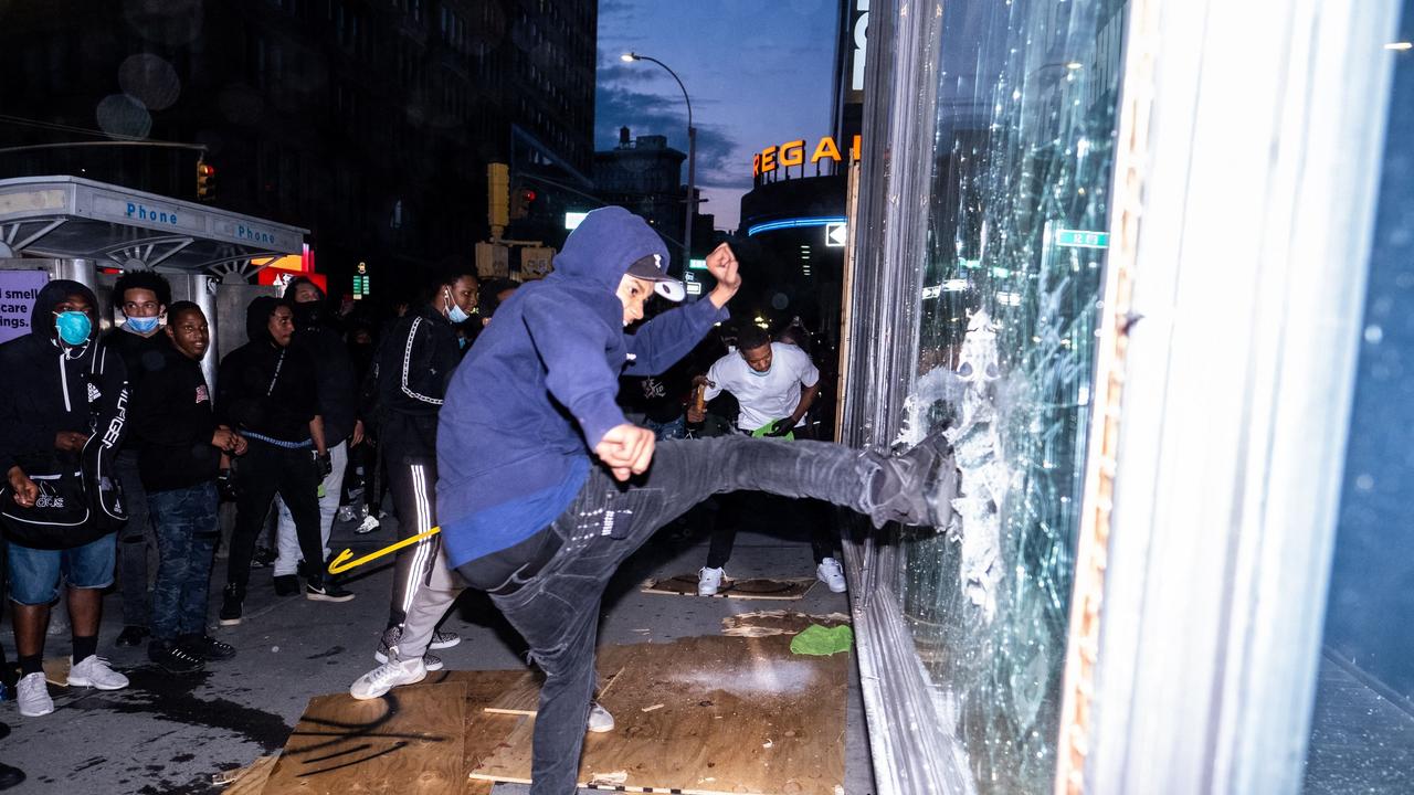 A man kicks the window of a Zumiez skate store on Monday. Picture: Stephen Yang / MEGA