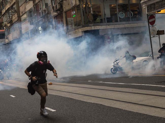 TOPSHOT - CORRECTION - Riot police deploy tear gas as they clear protesters from a road during a rally against a new national security law in Hong Kong on July 1, 2020, on the 23rd anniversary of the city's handover from Britain to China. - Hong Kong police made the first arrests under Beijing's new national security law on July 1 as the city greeted the anniversary of its handover to China with protesters fleeing water cannon. (Photo by DALE DE LA REY / AFP) / âThe erroneous mention[s] appearing in the metadata of this photo by DALE DE LA REY has been modified in AFP systems in the following manner: [tear gas] instead of [flash bangs]. Please immediately remove the erroneous mention[s] from all your online services and delete it (them) from your servers. If you have been authorized by AFP to distribute it (them) to third parties, please ensure that the same actions are carried out by them. Failure to promptly comply with these instructions will entail liability on your part for any continued or post notification usage. Therefore we thank you very much for all your attention and prompt action. We are sorry for the inconvenience this notification may cause and remain at your disposal for any further information you may require.â