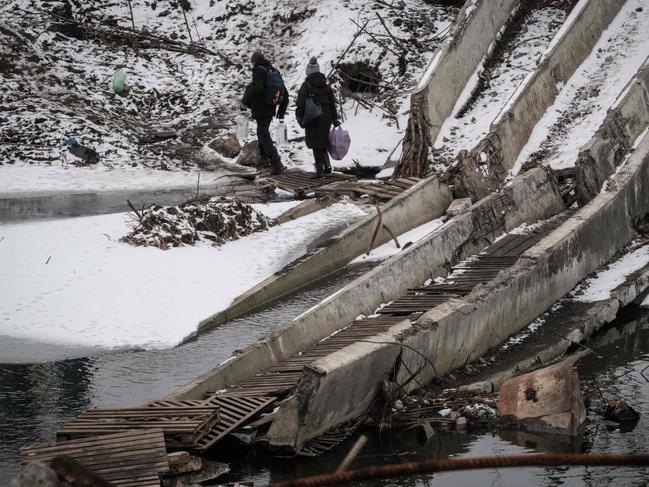 People walk on a destroyed bridge to cross a canal towards the disputed area in Bakhmut on February 1, 2023, amid the Russian invasion of Ukraine. Picture: AFP