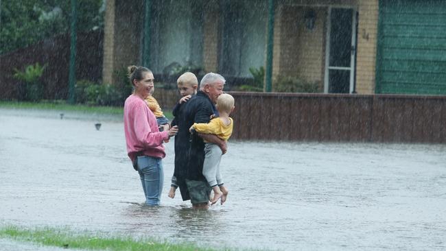 A man crosses flood waters to collect children at Richmond. Picture: John Feder/The Australian.