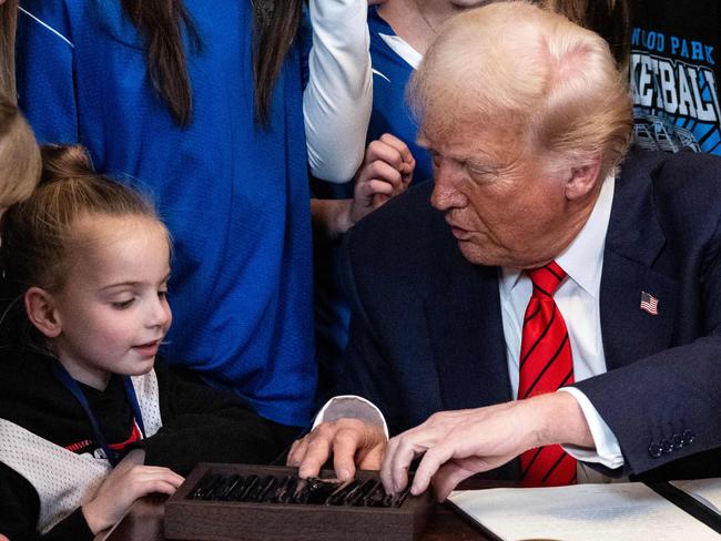 US President Donald Trump speaks with a little girl as he selects a pen to sign the No Men in Women's Sports Executive Order at the White House. Picture: AFP