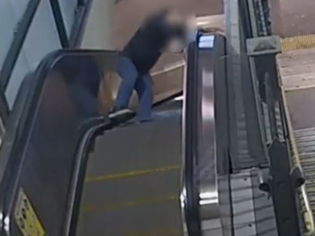 A man stumbles and falls down the escalator at Flinders St station.