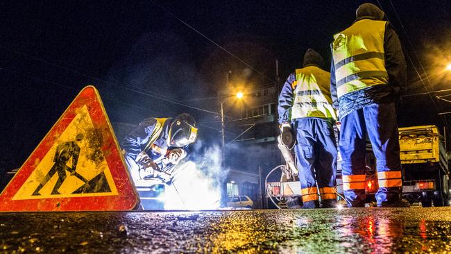 Low angle view of street workers and a welder while repairing the rail tracks in the city at night. Road sign is in front and truck with equipment is in the background. Picture: EXTREME-PHOTOGRAPHER/iStock