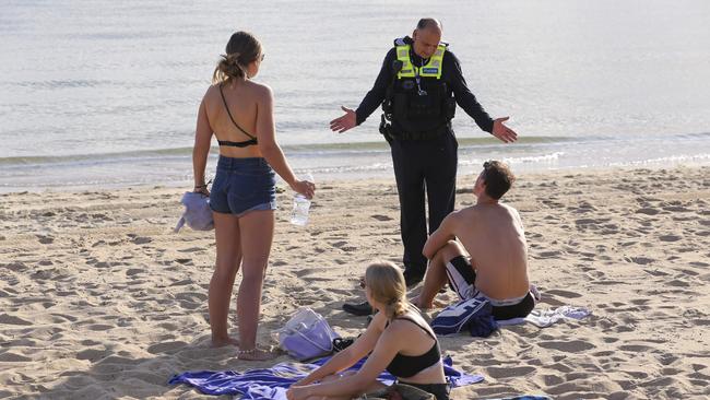 Police talk with beachgoers at St Kilda on Friday. Picture: Wayne Taylor