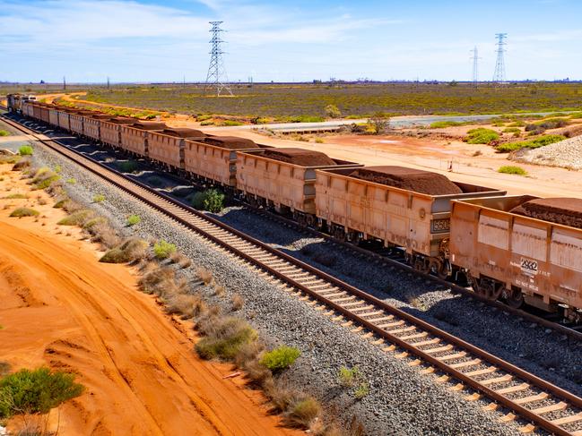 A freight train carrying iron ore travels along a rail track towards Port Hedland, Australia, on Monday, March 18, 2019. A two-day drive from the nearest big city, Perth, Port Hedland is the nexus of Australias iron-ore industry, the terminus of one of Australias longest private railways that hauls ore about 400 kilometers (250 miles) from the mines of BHP Group and Fortescue Metals Group Ltd. The line ran a record-breaking test train weighing almost 100,000 tons that was more than 7 kilometers long in 2001, and even normal trains haul up to 250 wagons of ore. Photographer: Ian Waldie/Bloomberg via Getty Images