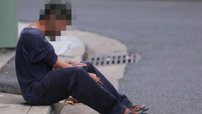 This addict in tracksuit and thongs sat down on the kerb in a laneway in Surry Hills and spent 10 minutes trying to find a vein. Picture: John Grainger