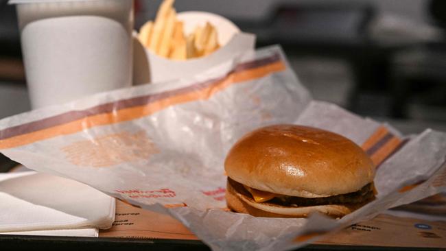 A double cheeseburger with fries and a soft drink. (Photo by Kirill KUDRYAVTSEV / AFP)