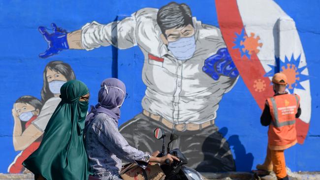 Two women on a motorcycle ride past Jakarata’s new mural. Picture: AFP