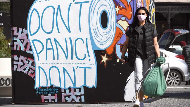 A face mask-clad woman passes a pertinent piece of graffiti art in the locked-down inner Melbourne suburb of Prahran on Thursday. Picture: AFP