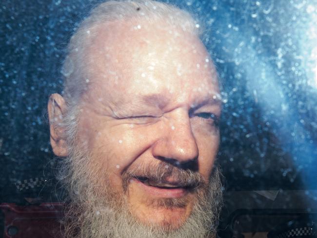 Julian Assange gestures to the media from a police vehicle on his arrival at Westminster Magistrates court. Picture: Getty