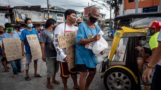 Drivers of the Philippines iconic Jeepney taxis queue up to receive food and aid from a concerned resident on a road a Manila road. Picture: AFP