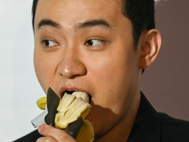 Chinese-born crypto founder Justin Sun eats a banana artwork composed of a fresh banana stuck to a wall with duct tape, in Hong Kong on November 29, 2024, after buying the provocative work of conceptual art by Italian artist Maurizio Cattelan at a New York auction for $6.2 million. The debut of the edible creation entitled "Comedian" at the Art Basel show in Miami Beach in 2019 sparked controversy and raised questions about whether it should be considered art -- Cattelan's stated aim. (Photo by Peter PARKS / AFP)