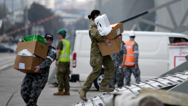 ADF personnel are seen carrying supplies on to HMAS Adelaide at Garden Island Naval Precinct on Saturday. Picture: AAP