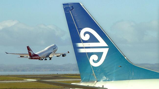 (FILES) This file photo taken on December 5, 2003 shows an Air New Zealand Boeing 737 sitting at a departure gate while an Australian Qantas Boeing 747-400 takes-off from Auckland Airport in Auckland. Thousands of airline passengers were stranded in Auckland on September 18, 2017 after a pipeline leak cut jet fuel supplies to New Zealand's largest airport, forcing planes to remain grounded, authorities said. / AFP PHOTO / Dean TREML