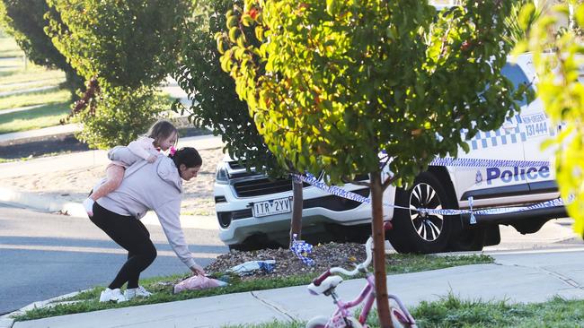 A woman and child place flowers at the scene. Picture: David Crosling