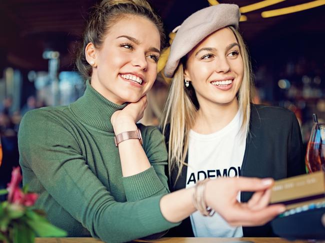 Girlfriends are paying their cocktails using contactless credit card in the bar