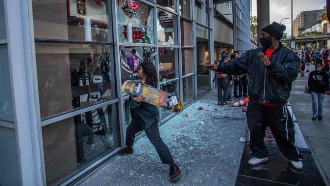 A demonstrator uses a skateboard to vandalise a restaurant in downtown Los Angeles. Picture: AFP