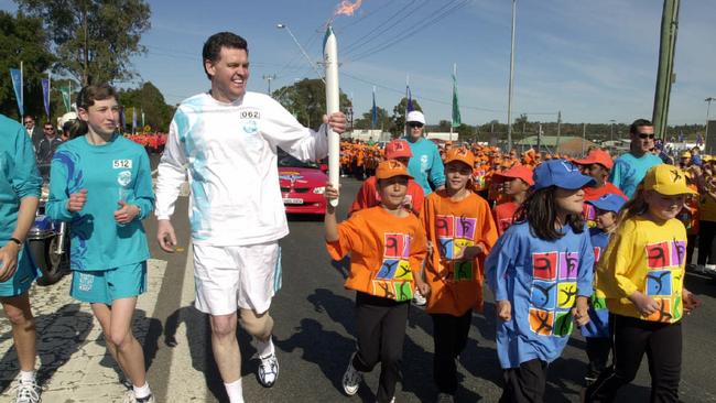 Olympics Minister Michael Knight holds the Olympic flame and runs with children during the Penrith to Bowral leg of Sydney 2000 Olympic Torch Relay.