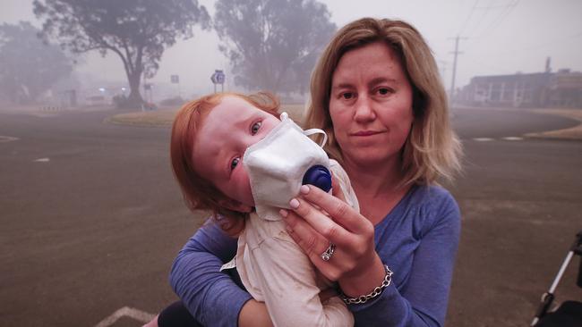 Laura Langmead puts a breathing mask on her one-year-old daughter Evie before being evacuated from Mallacoota on Thursday. Picture: David Caird