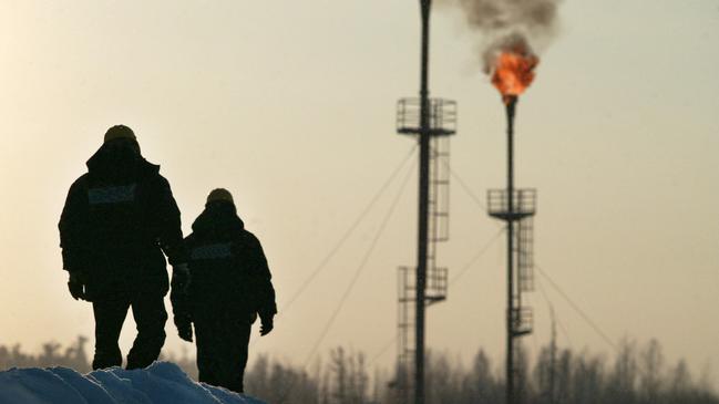 Two workers walk near a gas flare-off at the Yukos owned Mamontovskoye oil-field in the Khanty-Mansy. Picture: Dmitry Beliakov/Bloomberg News.