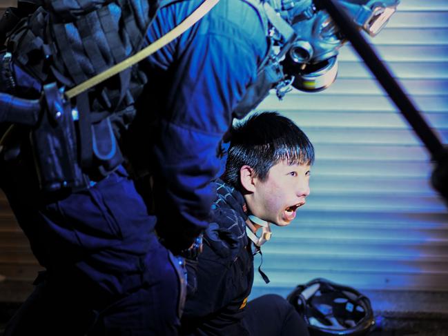 A pro-democracy protester is held by police outside Tsim Sha Tsui Police station. Picture: AFP