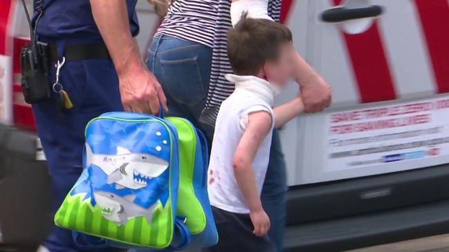 The injured boy is accompanied to an ambulance.