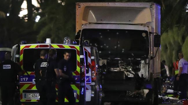 Police officers and rescued workers stand near a van that ploughed into a crowd leaving a fireworks display in the French Riviera town of Nice on July 14, 2016. The mayor of the French city of Nice said dozens of people were likely killed after a van rammed into a crowd marking Bastille Day in the French Riviera resort today and urged residents to stay indoors. / AFP PHOTO / VALERY HACHE